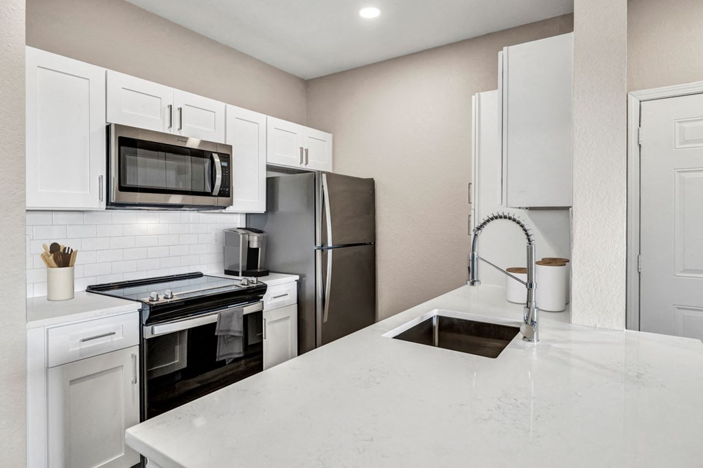Kitchen with Stainless Steel Appliances and Quartz Countertops a kitchen with white cabinets and stainless steel appliances at Stonelake at the Arboretum, Austin, TX, 78759